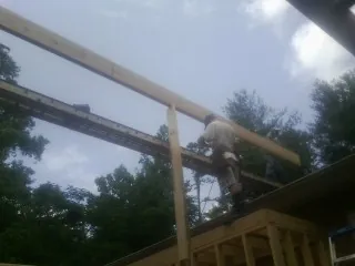 Carpenter setting a ridge beam over a new addition frame — Ice Dam Removal by Roofing Brothers in Sunbright