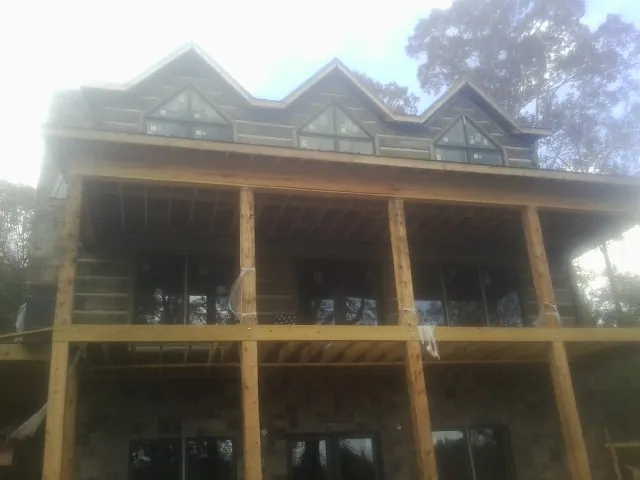 Dormers and porch framing on a large log home under construction — Roof Coating work by our crew in Sunbright