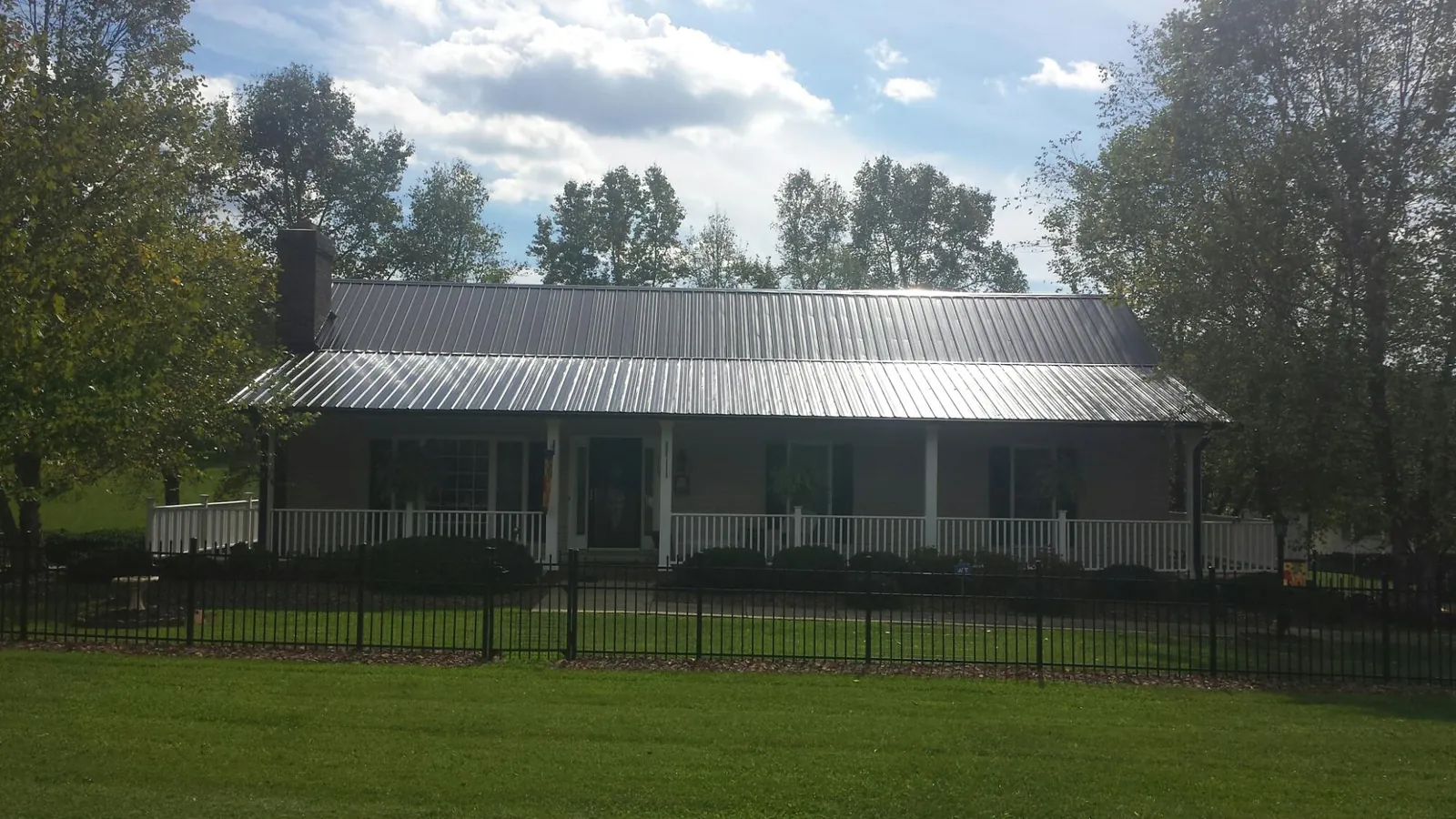 Gray metal roof on a brick ranch with a full width front porch — Gutter Guard Installation work by our crew in Sunbright