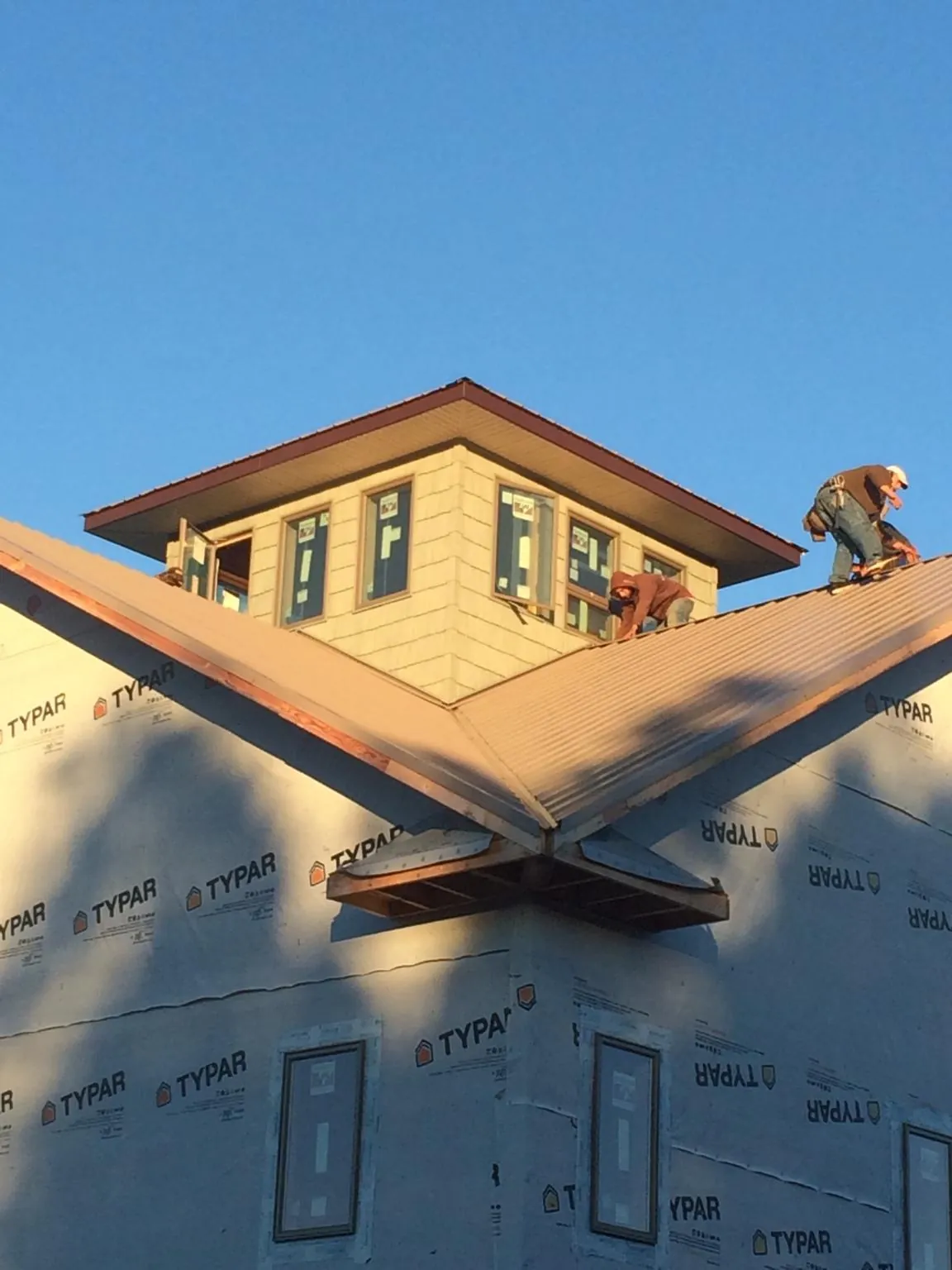 Roofers working around a rooftop cupola on a new metal roof at sunset — Roof Waterproofing in Sunbright by Roofing Brothers